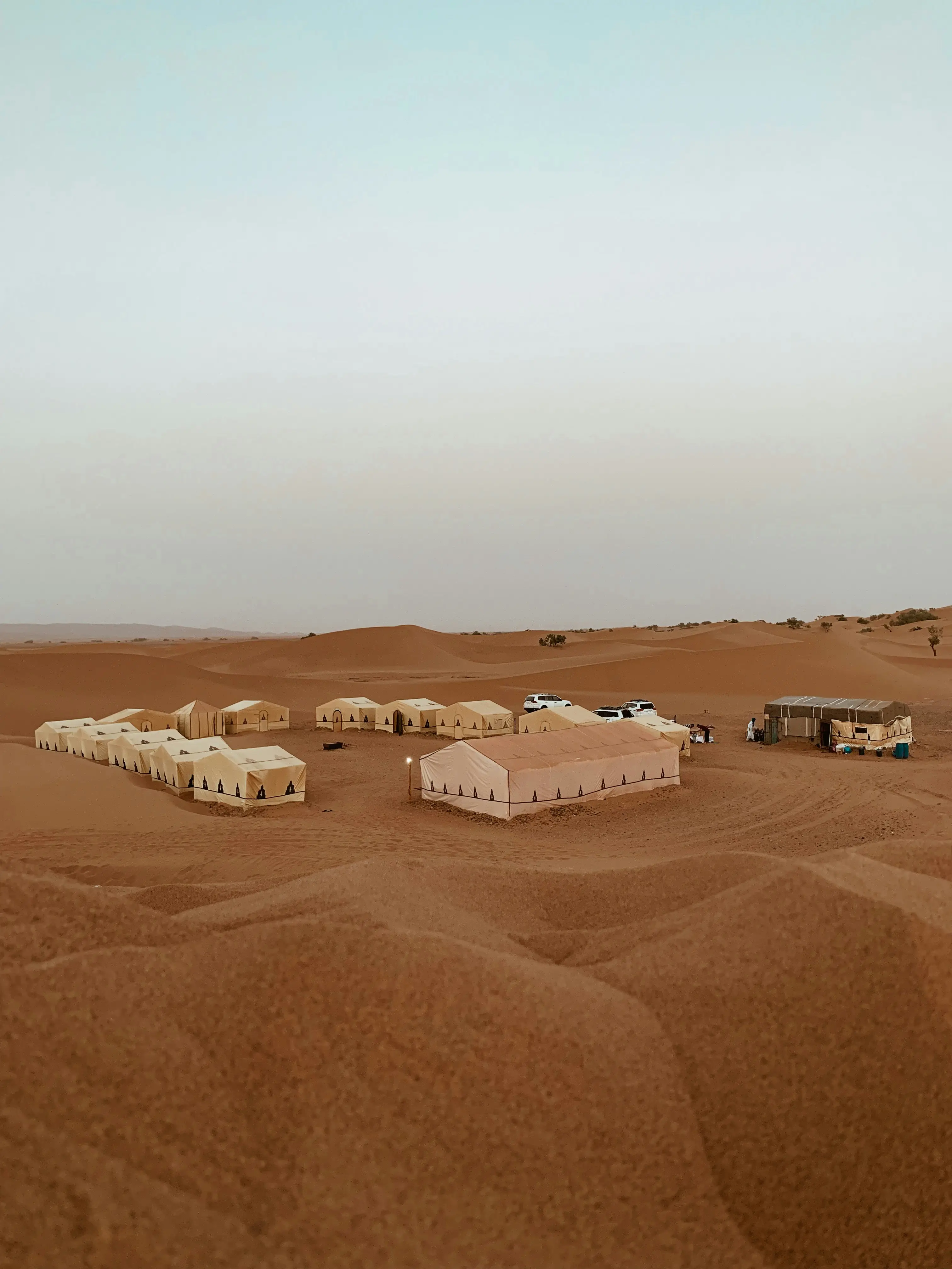 Traveler packing essentials for Morocco desert tour including clothing, camera, and desert gear laid out on bed